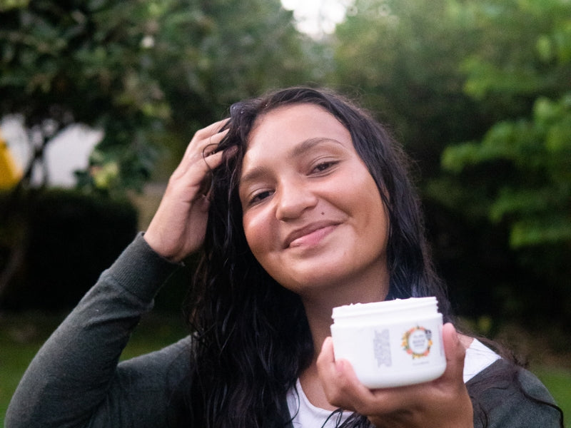 Woman holding Skin Balm Apothecary Nourish Conditioner outdoors.